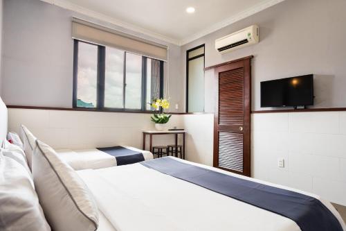 a hotel room with two beds and a flat screen tv at Văn Hoa Hotel in Ho Chi Minh City