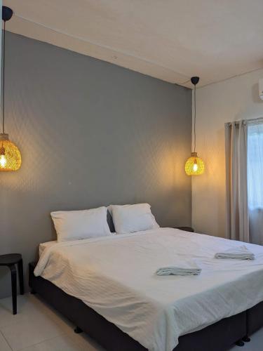 um quarto com uma grande cama branca e 2 luzes em V at Panus em Phanat Nikhom