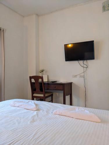 a bedroom with a bed and a desk and a television at V at Panus in Phanat Nikhom
