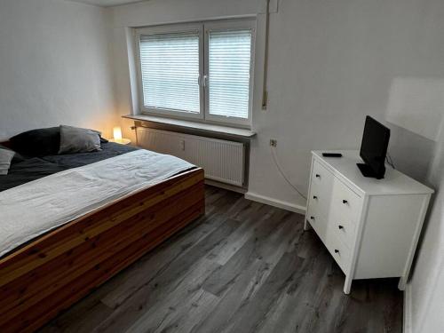 Dormitorio con cama y tocador con TV en Mittelpunkt der Stadt, en Vellmar