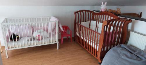 two white cribs in a room with wooden floors at Rodinný apartmán Alma in Bojnice