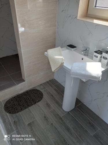 La salle de bains est pourvue d'un lavabo blanc et d'une douche. dans l'établissement HomeHotel, à Tchornomorsk