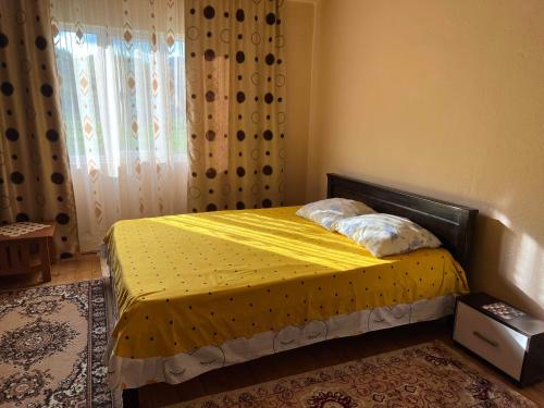 ein Schlafzimmer mit einem Bett mit gelber Bettwäsche und einem Fenster in der Unterkunft Casa Danut in Vidra