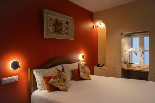 a bedroom with a bed with an orange wall at Garlande Hôtel Avignon Centre in Avignon
