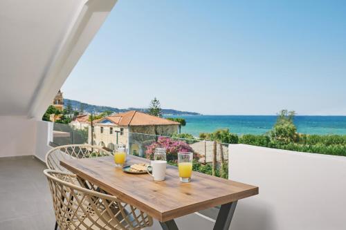 a wooden table on a balcony with two glasses of orange juice at Sofita Sea View Apartment in Argassi