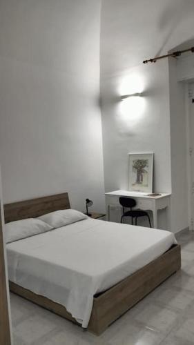 a white bedroom with a bed and a desk at Alloggio privato "Ballatoio233" in Bisceglie