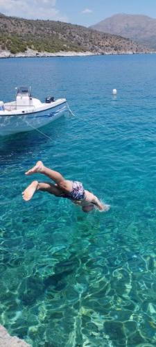 a person swimming in the water next to a boat at Suite of Villa Lagkadaki in Agriliá