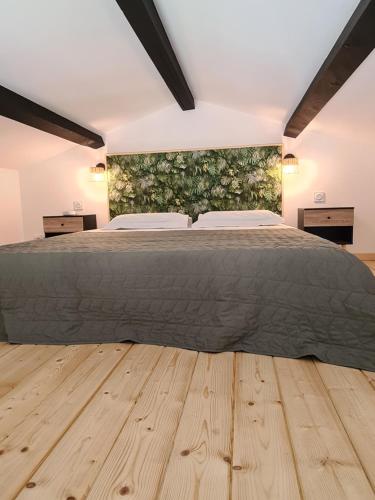 1 dormitorio con 1 cama grande y suelo de madera en Gîte spa la parenthèse en Sauve