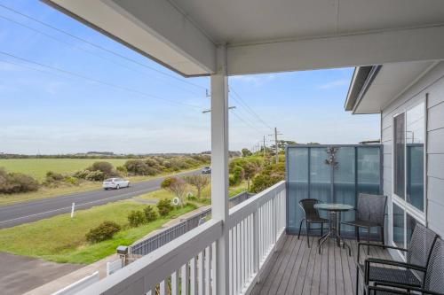 a balcony with a table and chairs and a road at Ocean Pearl by Ready Set Stay - BYO LINEN & TOWELS in Surf Beach