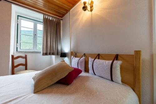 a bedroom with a white bed with a red pillow at A Casa da Rapariga de Cabelo Azul in Manteigas
