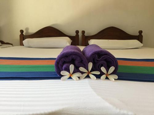 Una cama con mantas moradas y flores. en New Manik Homestay, en Negombo