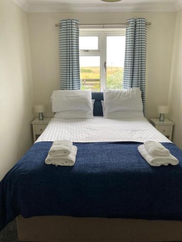 a bedroom with a large bed with towels on it at Stoneyfield South Cottage in Stornoway