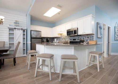 a kitchen with white cabinets and a counter with stools at Phoenix V 105 condo in Orange Beach