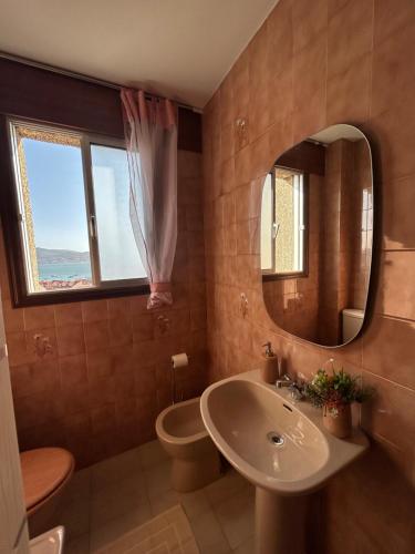a bathroom with a sink and a toilet and a mirror at Apartamento Son Ría in Nigrán