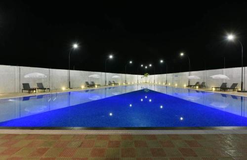 a large swimming pool at night with blue water at Ivy Zen 1 BHK with Common Pool 12 kms from Imagicaa in Jambhulpāda