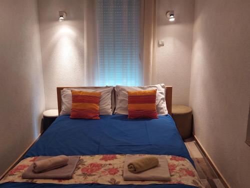 ein Schlafzimmer mit einem blauen Bett mit zwei Kissen und einem Fenster in der Unterkunft Excellency apartmani in Banja Luka