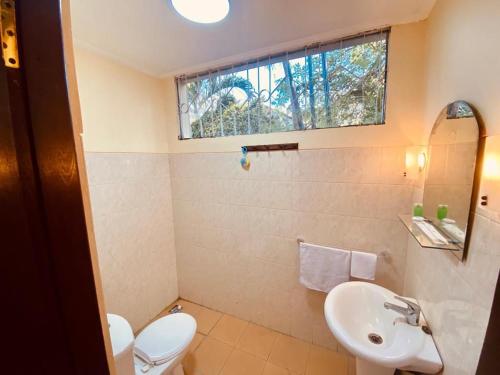 a bathroom with a toilet and a sink and a window at Villa Kinandari Bukit Jimbaran in Jimbaran