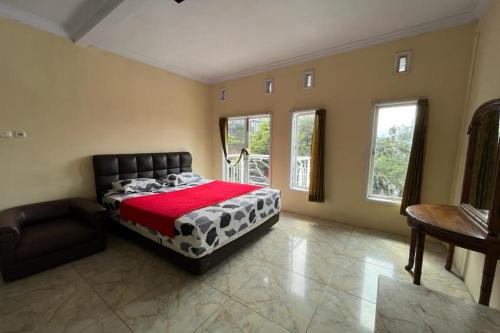 a bedroom with a bed and a chair and windows at OYO LIFE 92844 Penginapan Cibodas in Pasuruan