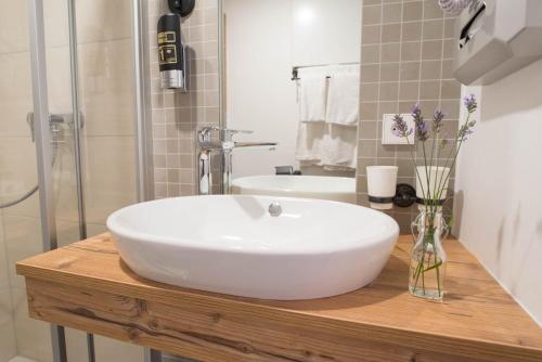 een witte wastafel op een houten aanrecht in een badkamer bij Alpenhotel Dahoam in Schleching