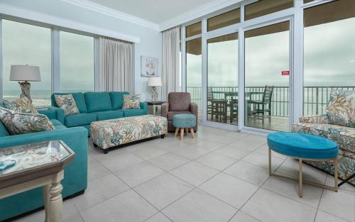 een woonkamer met een blauwe bank en stoelen bij Phoenix Orange Beach II 1105 condo in Orange Beach