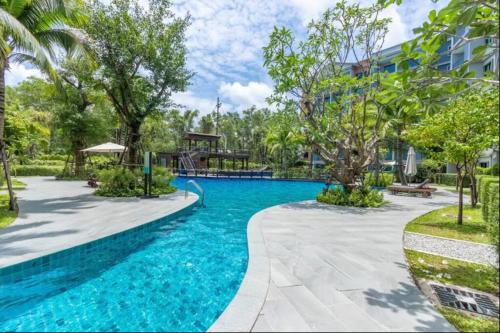 uma piscina num resort com árvores e um edifício em 2 Bedroom Apartment in Naiyang - The Title Residences, Naiyang em Praia de Nai Yang