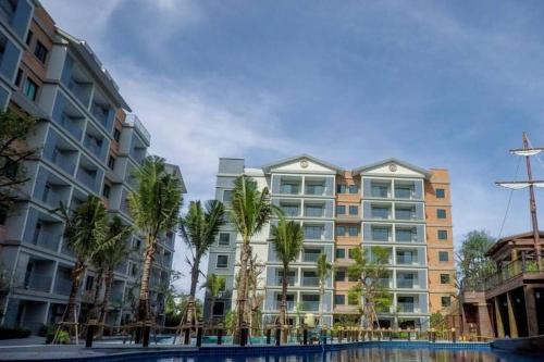 a large building with palm trees in front of it at 2 Bedroom Apartment in Naiyang - The Title Residences, Naiyang in Nai Yang Beach