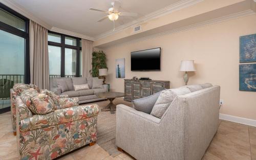 a living room with two couches and a flat screen tv at The Oasis 2214 formerly Phoenix West II 2214 in Orange Beach