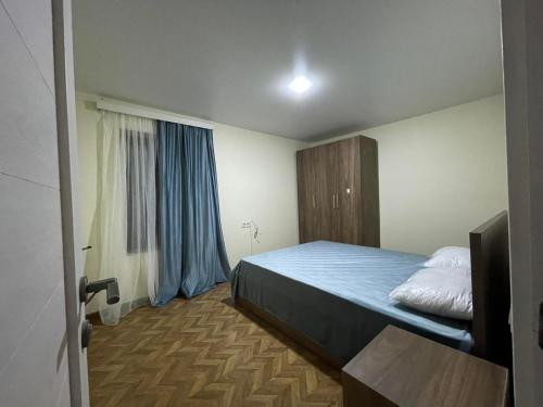 - une chambre avec un lit doté de draps bleus et une fenêtre dans l'établissement Flats at Era Square, à Batoumi