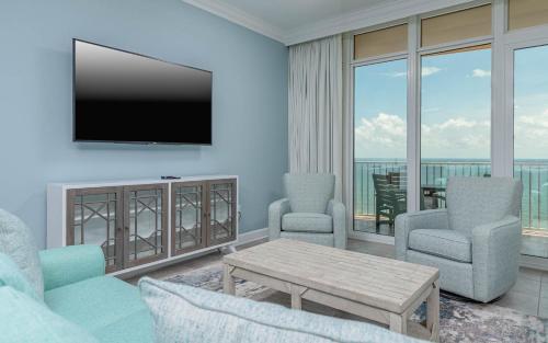 a living room with a television and a table and chairs at Phoenix Orange Beach II 1103 condo in Orange Beach
