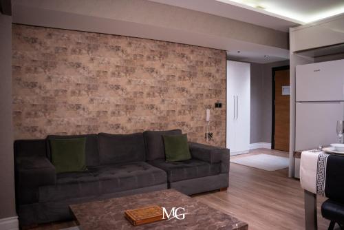a living room with a couch and a brick wall at MG HİLL RESİDENCE BUTİK OTEL in Yeşilyurt