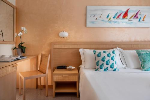 ein Hotelzimmer mit einem Bett und einem Schreibtisch mit einem Stuhl in der Unterkunft Corallo Wellness Hotel in Diano Marina