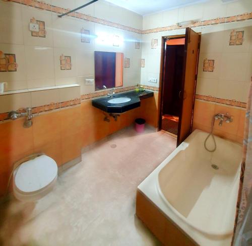 y baño con bañera, aseo y lavamanos. en Hotel Shrinath Palace, en v