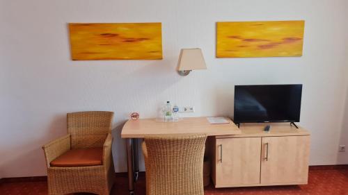 Habitación con escritorio, TV y 2 cuadros. en Terra Ventura Hotel, en Gondorf