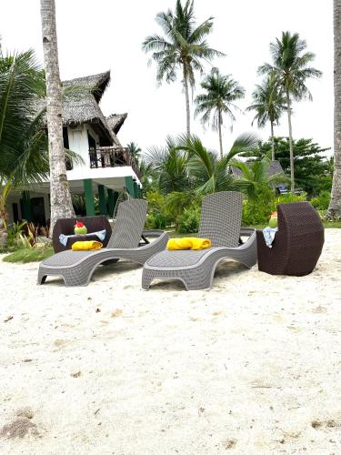 a group of chairs on the sand on the beach at Entire Private Beachfront Villa in Siargao in General Luna