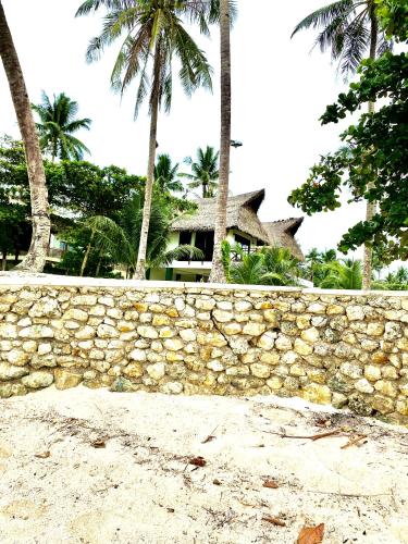 a stone wall with palm trees in front of a house at Entire Private Beachfront Villa in Siargao in General Luna