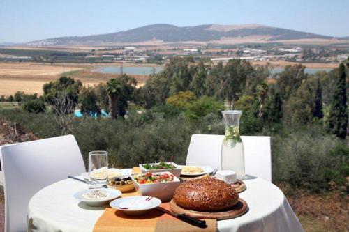 una mesa con un mantel blanco y comida en ella en Gilboa Guest House - Benharim en Gid‘ona