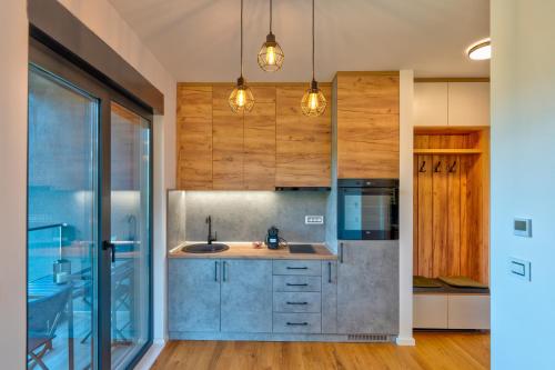 uma cozinha com armários de madeira e um lavatório num quarto em Zlatibor Pine View em Zlatibor