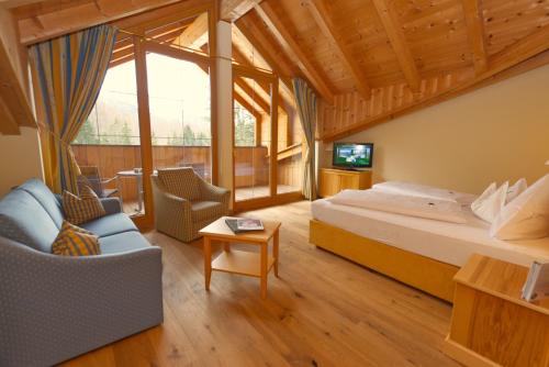 a bedroom with a bed and a couch and a tv at Hotel Alpen Residence in Ehrwald