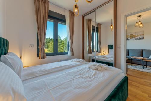 um quarto com uma grande cama branca e uma grande janela em Zlatibor Pine View em Zlatibor