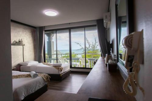 um quarto de hotel com duas camas e uma grande janela em Pimpimarn Hotel em Mae Pim