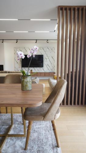 a living room with a wooden table with a vase of flowers at Beachfront 2BR Apartment with Balcony and Sea View, Biser Mora in Rafailovici