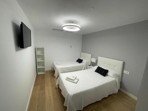 two beds in a room with white walls and wooden floors at Apart 1 en PLANTA BAJA CON PEQUEÑO JARDÍN EN PRIMERA LÍNEA DE PLAYA in Almería