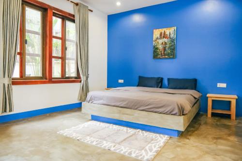 a blue bedroom with a bed and a blue wall at The Big Easy Siem Reap in Siem Reap
