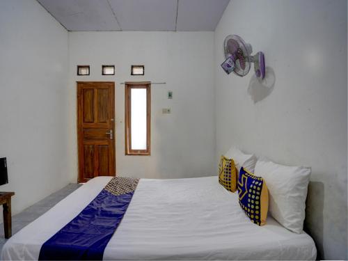 a bedroom with a bed with white sheets and a window at SPOT ON 92855 Griya Sandi Syariah Rogojampi in Banyuwangi