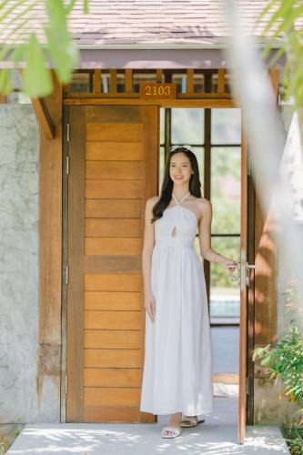a woman in a white dress standing in front of a door at Bor Saen Pool Villa in Bor Saen