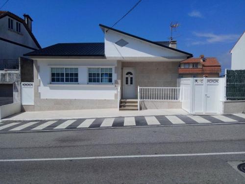 a small white house with a gate and a street at Vista a las Cíes in Moaña