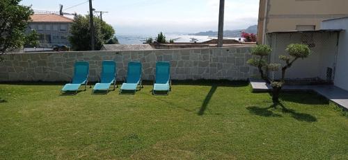 three blue chairs sitting in the grass in a yard at Vista a las Cíes in Moaña