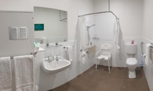 Baño blanco con lavabo y aseo en Aart Apartments, en Port Lincoln