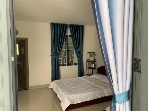 Schlafzimmer mit einem Bett und einem Fenster mit blauen Vorhängen in der Unterkunft Luxury House with 3 bedrooms & balcony-terrace in Ho-Chi-Minh-Stadt