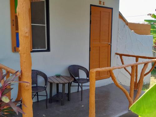 a porch with chairs and a table and a door at Khaolak Banana Bungalow in Khao Lak